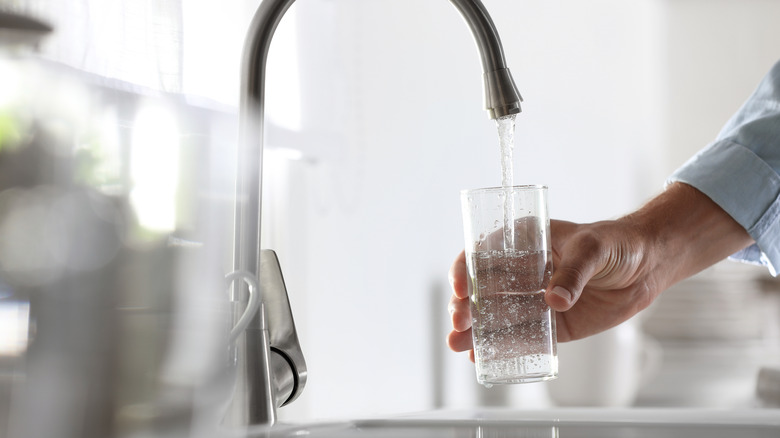 Person filling water glass at sink