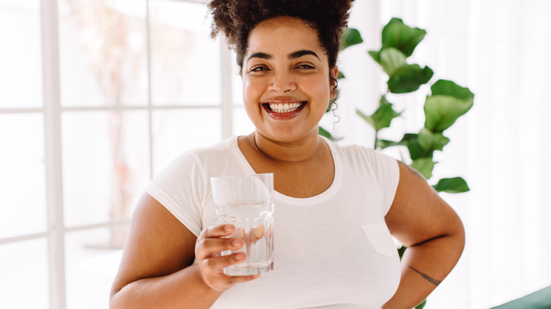 Smiling woman holding glass of water