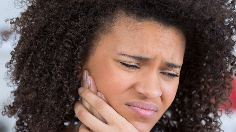 Woman wincing rubbing her jaw in pain