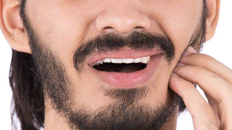Bearded man massaging one side of his jaw