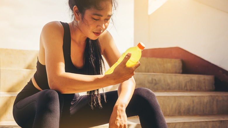 Asian woman holding electrolyte drink