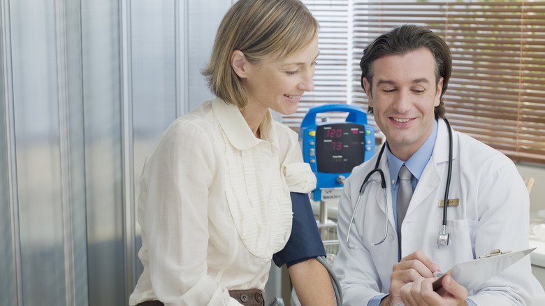 Doctor checking woman's blood pressure