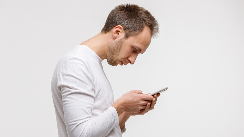 A man hunched over his phone