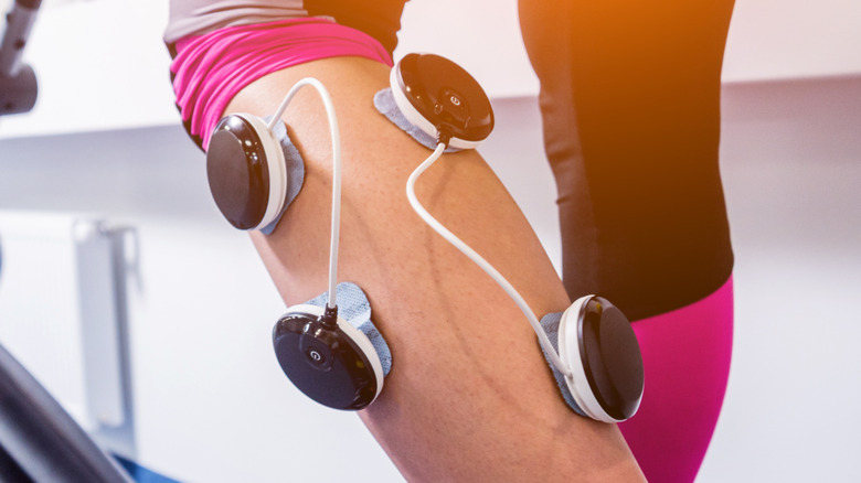electronic stimulation therapy on a woman's calf muscle