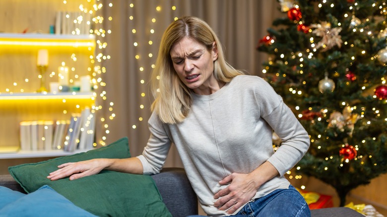 Woman on couch holding stomach in pain