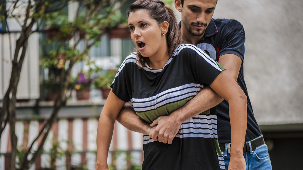 Man giving woman Heimlich manuever
