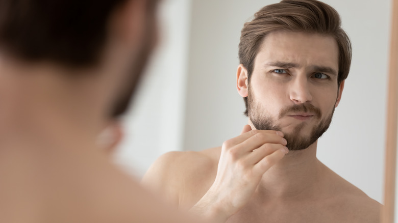 man examining face in mirror