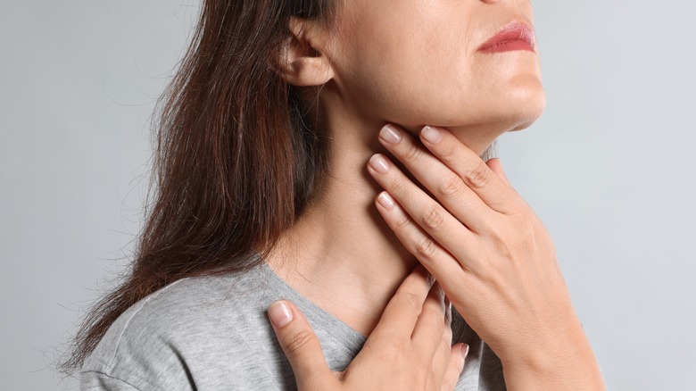 Woman touches neck doing a thyroid check