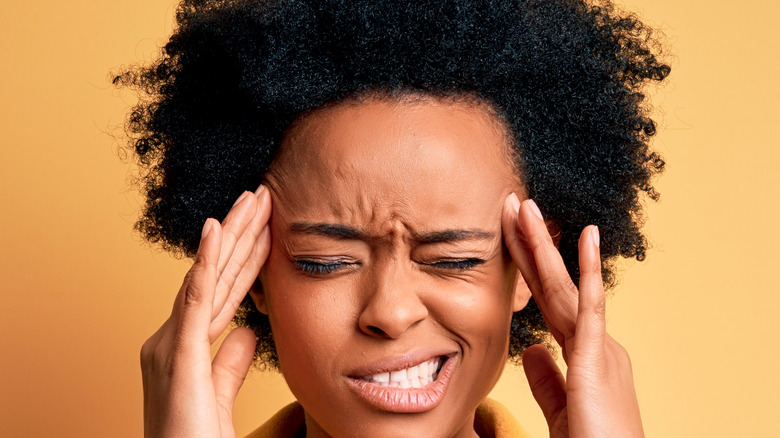 a woman holding her head because of a migraine