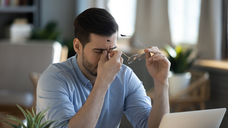 A man rubs his eyes