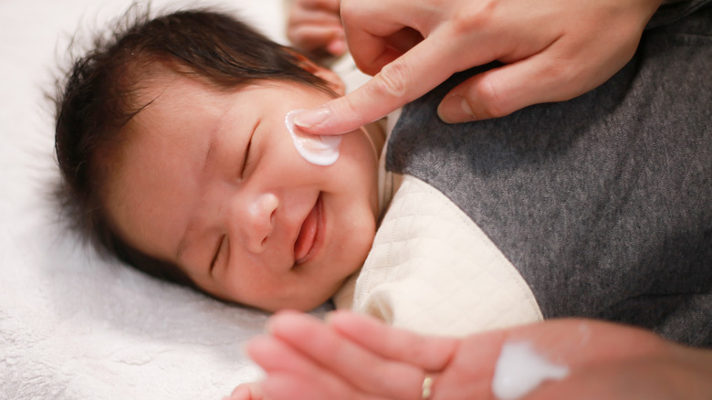 a mother moisturizing baby 