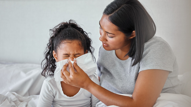 Mother cleaning young girl's nose