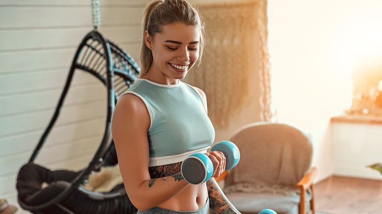 Smiling woman at home doing dumbbell curls