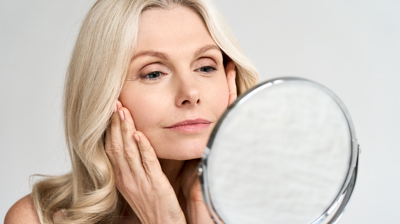 Woman looking at face in mirror