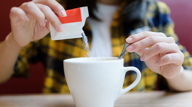 woman pours sugar in coffee