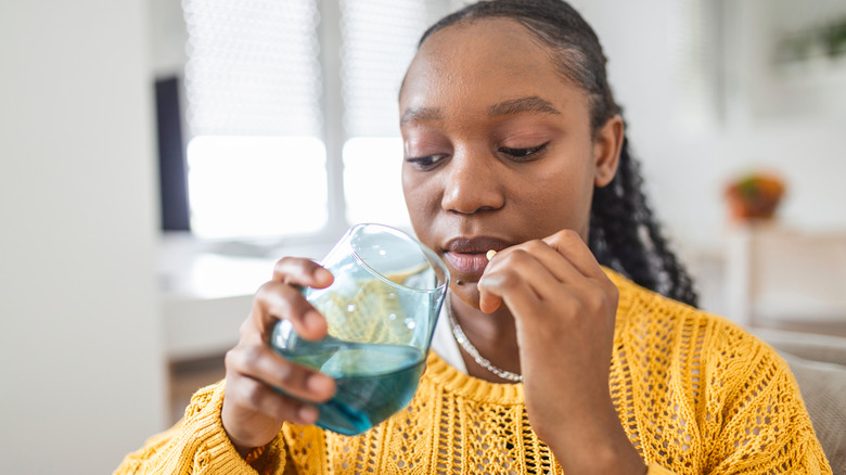 Young woman taking pill