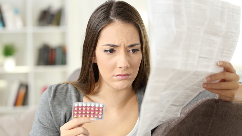 Worried woman reading birth control instructions