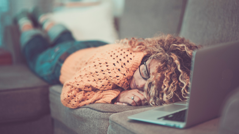 Woman asleep on couch with computer