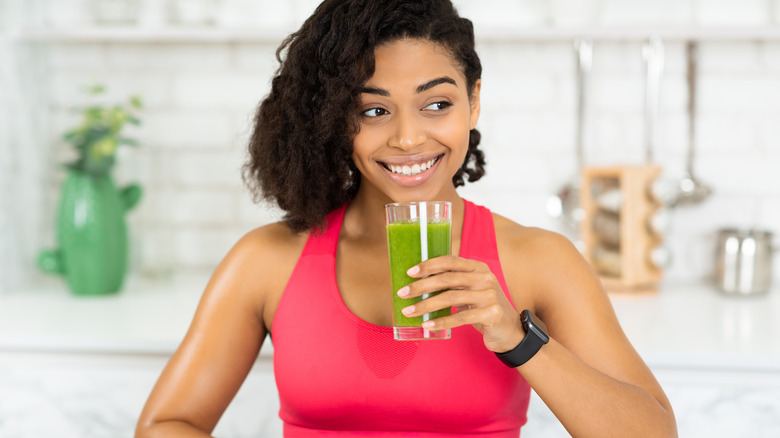 Black fit woman drinking green smoothie