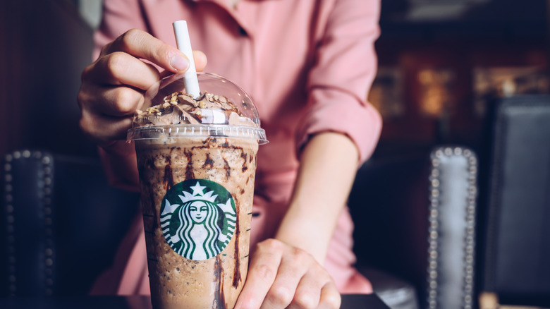 Woman putting straw in a Starbucks drink