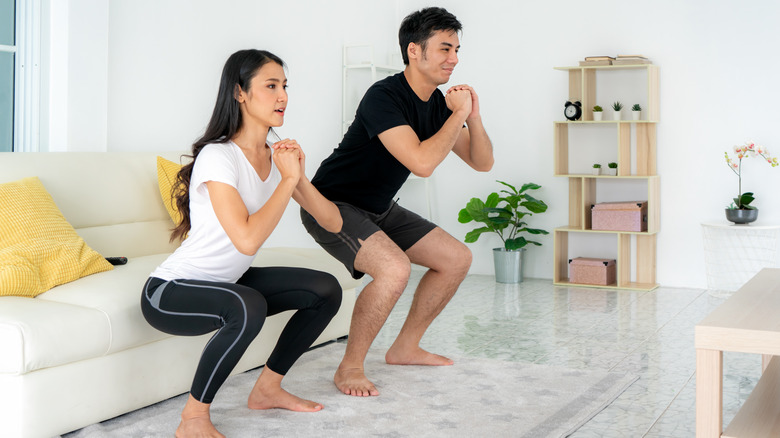 couple doing squats at home