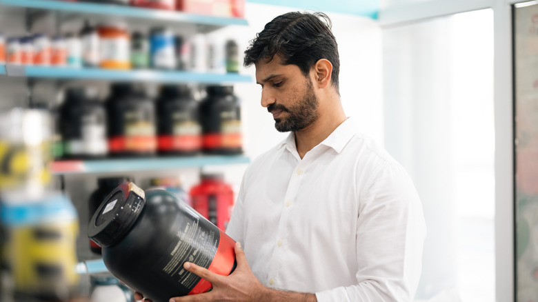 man reading label on whey protein container