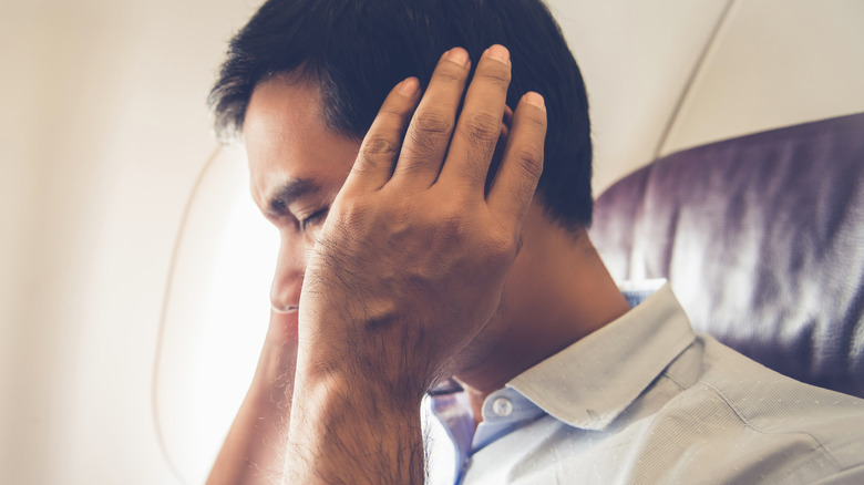 Man covering ears on airplane