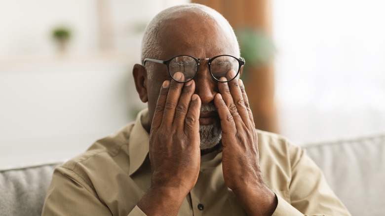 older man rubbing eyes