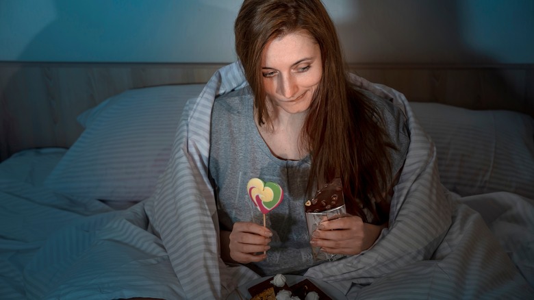 Woman eating candy in bed
