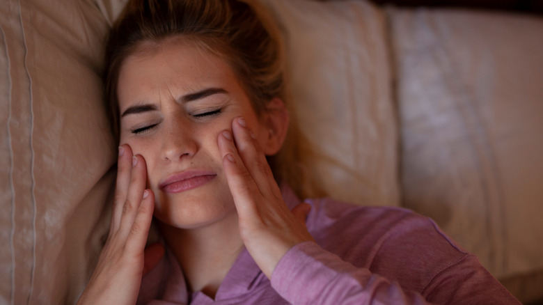 woman with bruxism massaging face