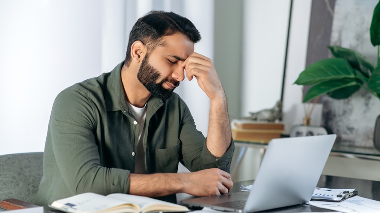 Man holding his head while working