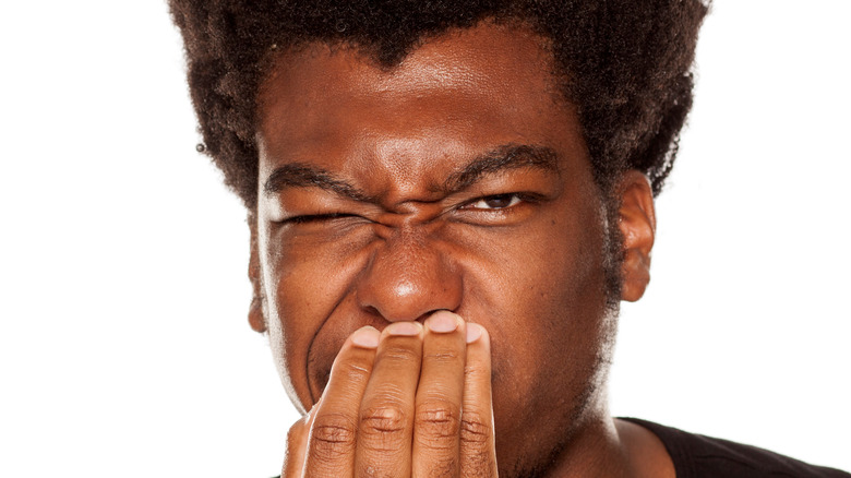 Person covering mouth from gross burp smell