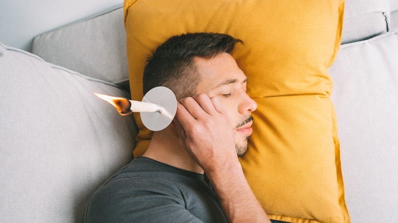 Man performing ear candle treatment