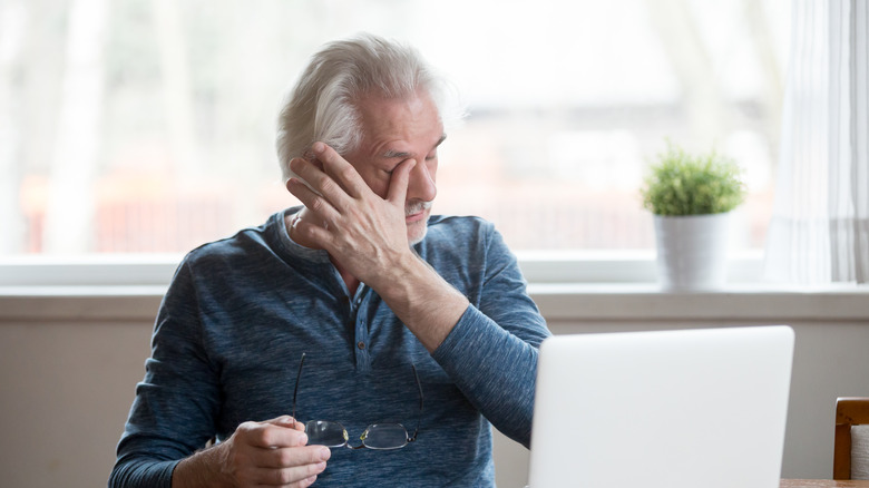 An older man wipes his eyes