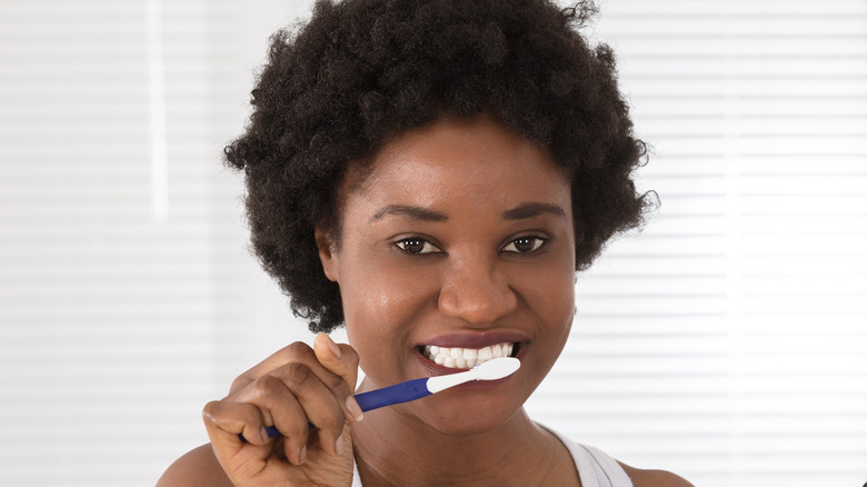 african woman using toothbrush
