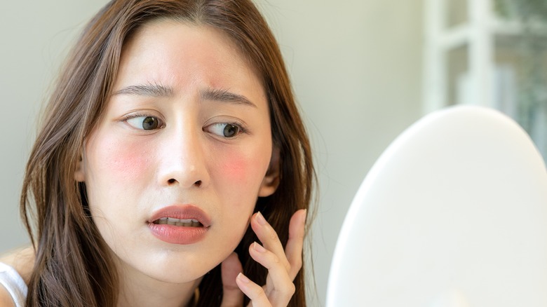 Woman examining face in mirror