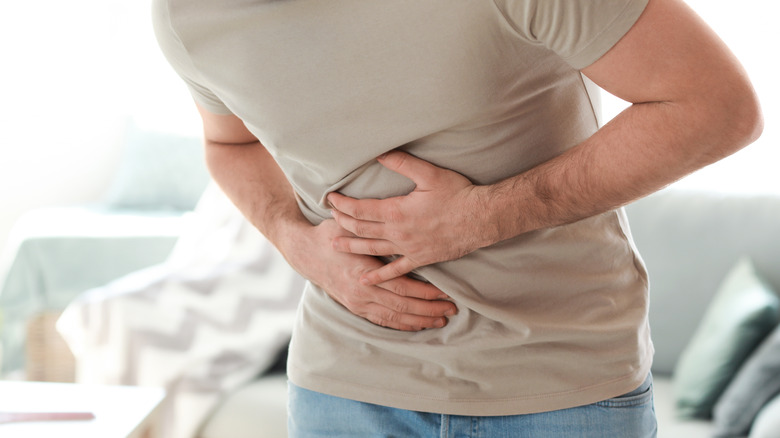 Man holds his abdomen in pain