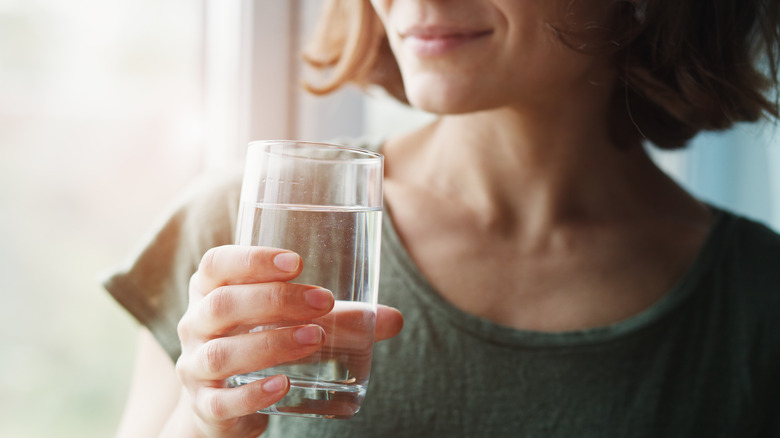 Woman smiling holding a glass of water