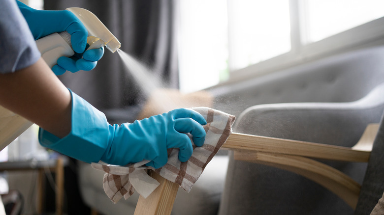 Close up of hands wearing gloves while disinfecting the arm of a couch
