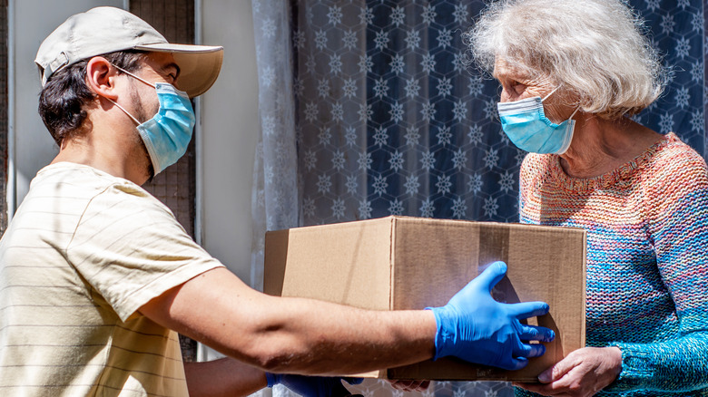 A young man delivers groceries to an elderly woman