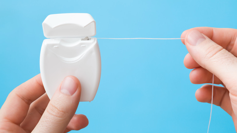 Hands holding string of floss