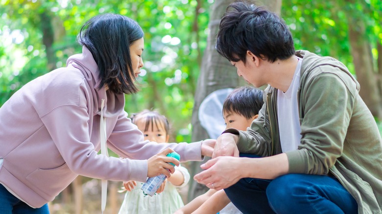 Family spraying themselves with bug repellent