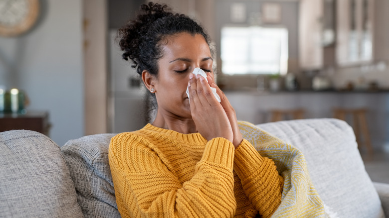 Indian woman with flu holding handkerchief to nose 