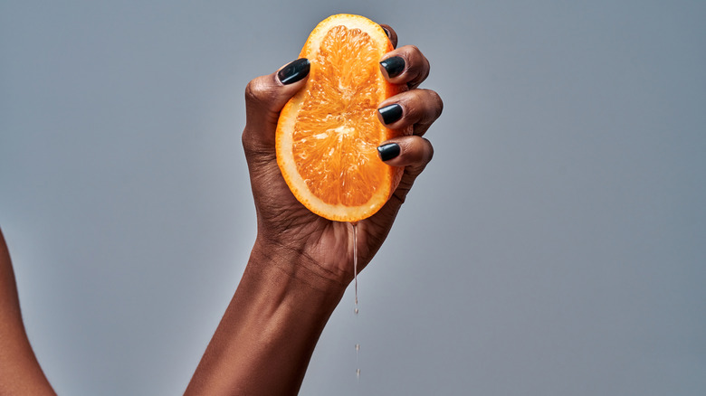 Hand squeezing orange slice