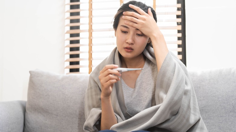 woman on couch checking temperature