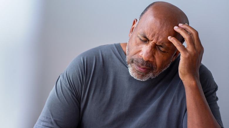 man with his eyes closed holding his head