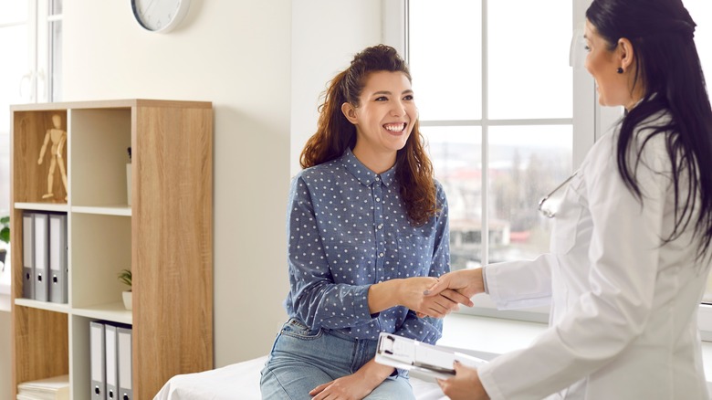 Smiling patient shaking doctor's hand