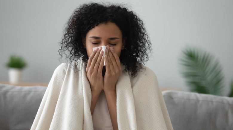 woman on the sofa sick and blowing her nose