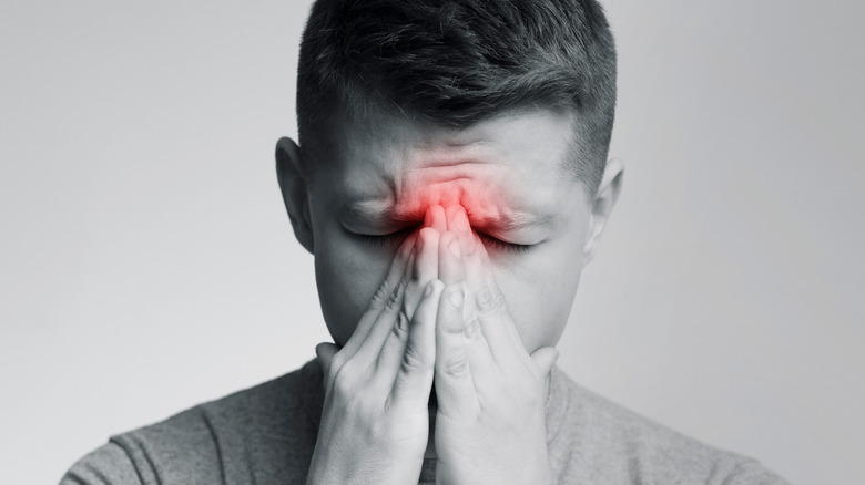Man blowing nose with red sinuses highlighted