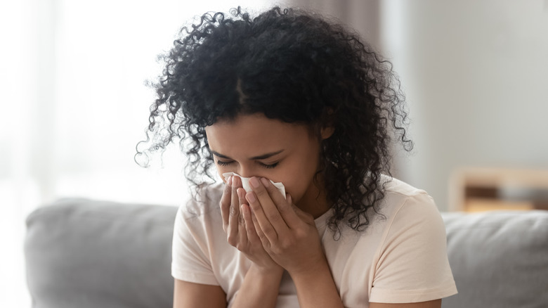 Woman sneezing into tissue